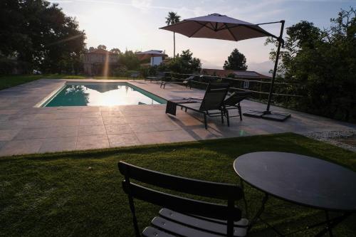 a patio with a table and an umbrella next to a pool at Quinta das Flores in Geraz do Lima