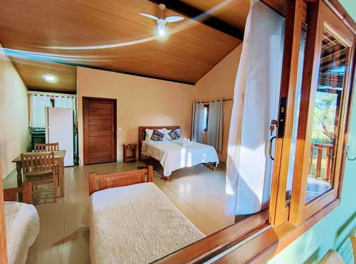 a bedroom with a bed and a room with a window at Chalé Céu de Minas in Visconde De Maua