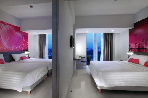 a bedroom with two beds and a large window at favehotel Pekanbaru in Pekanbaru