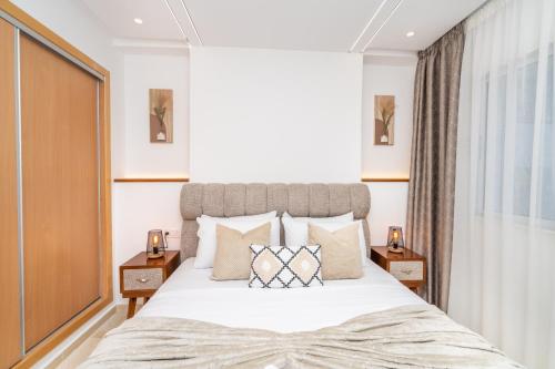 タンジェにあるCosy Place, Charmant 2 Chambres Neuf, Proche Golf Royal & Parc Perdicaris, 15' du Cap Spartel & du Centre Villeの大きな白いベッドと枕のある寝室