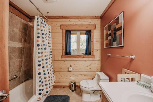 ein Badezimmer mit Toilette, Badewanne und Waschbecken in der Unterkunft Glacier Springs Cabin #21 - Log Cabin - Wi-Fi - Pets Ok in Glacier