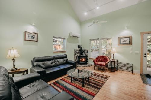 a living room with a black leather couch and a fireplace at Glacier Springs Cabin 12 - Wi-Fi - A-C - Evc in Glacier