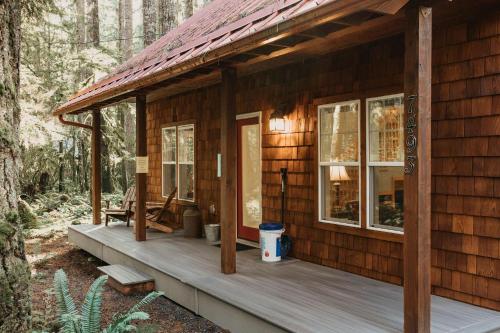 a wooden cabin with a porch in the woods at Glacier Springs Cabin 12 - Wi-Fi - A-C - Evc in Glacier