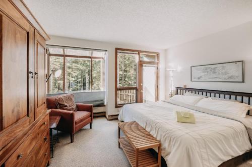 ein Schlafzimmer mit einem großen Bett und einem Stuhl in der Unterkunft Snowater Condo #41 - Wi-Fi - Sauna - Soaker Tub in Glacier