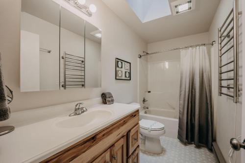 a white bathroom with a sink and a toilet at Glacier Springs Cabin #30 - Hot Tub - Wi-Fi - Pets Ok in Glacier