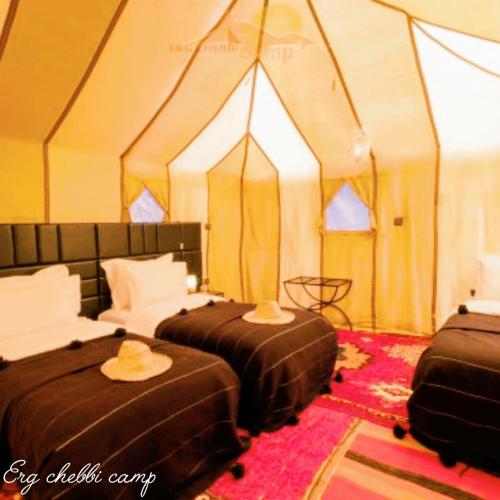 zwei Betten in einem Zelt mit Hüten darauf in der Unterkunft Erg Chebbi Camp in Merzouga