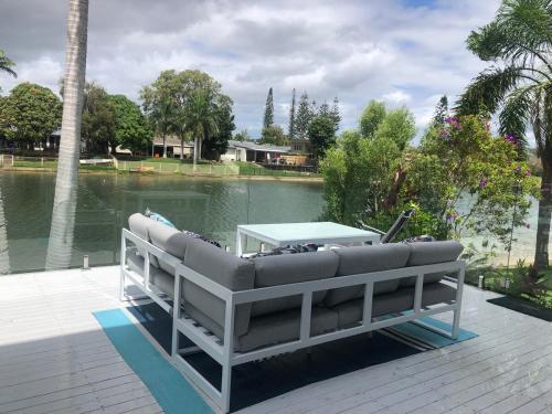 a couch sitting on a deck next to a lake at Waterfront 3 Bedroom House in Family Friendly Resort in Gold Coast