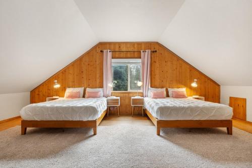 a attic room with two beds and a window at Riverfront w Cedar Hottub, Sauna, Movie Theatre in Granite Falls