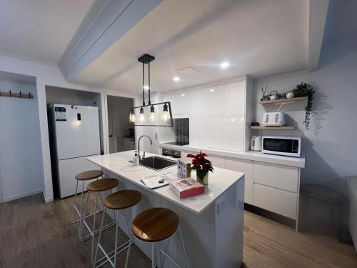 a kitchen with white cabinets and a counter with stools at Waterfront 3 Bedroom House in Family Friendly Resort in Gold Coast