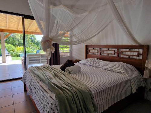 a bedroom with a large bed with a canopy at Kazacactus-villa 3 chambres piscine Marie-Galante in Beauséjour