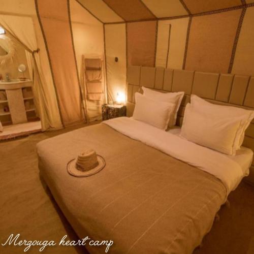 a bed with a hat sitting on top of it at Merzouga heart camp in Merzouga