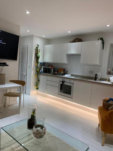 a kitchen with white cabinets and a table in a room at Ocean Drive Deluxe Apartment with complimentary Day Time Beach hut in Brean