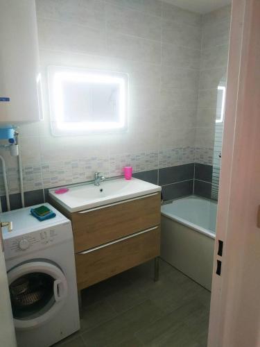 une salle de bain avec un lavabo et une machine à laver dans l'établissement Le Lagon Bleu - Fidji 12 - Rez de jardin privatif - Tennis - Piscine, à Fréjus