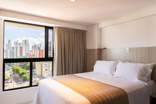 a hotel room with a bed and a large window at Move #914 - Apartamento Confortável by Carpediem in Tambaú