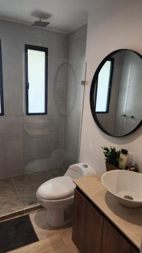 a bathroom with a toilet and a sink and a mirror at Campestre Apartment Loft in El Retiro