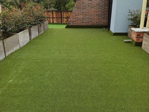 a yard with green grass and a brick fence at Campestre Apartment Loft in El Retiro