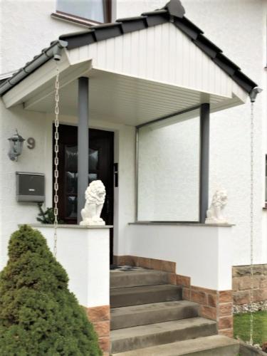 a white house with two white statues on the front door at Frau Holle in Wolfhagen