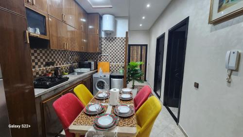 a small kitchen with a table with chairs and a tableablish at Appartement 7 min de l'aéroport de Marrakech in Marrakech