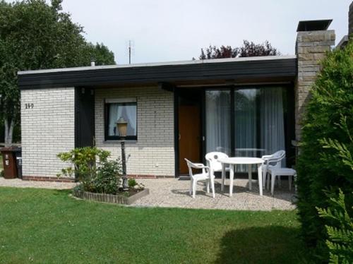 a house with a table and chairs in a yard at Bungalow 451 in Tossens in Tossenserdeich