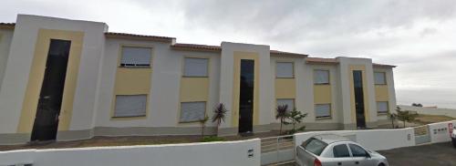 a building with a car parked in a parking lot at Alojamento Luna in Porto Judeu