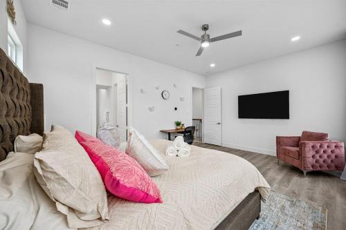 a bedroom with a bed with pink pillows and a flat screen tv at Pet-Friendly l Brand New Space l Downtown in Dallas