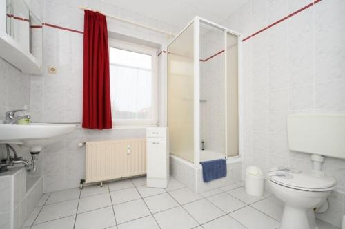 a white bathroom with a toilet and a sink at Aster in Graal-Müritz