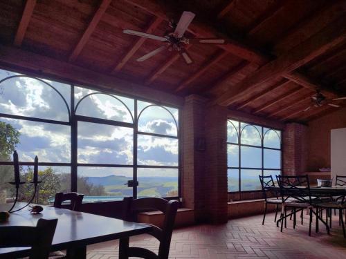 a large room with tables and chairs and large windows at Podere Rinascidentro in Asciano