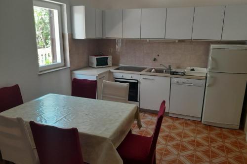 a kitchen with a table and a sink and a refrigerator at Apartments with parking space Lopar, Rab - 23747 in Lopar
