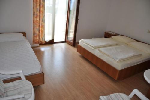 a bedroom with two beds and a table and a window at Apartments with parking space Lopar, Rab - 23747 in Lopar