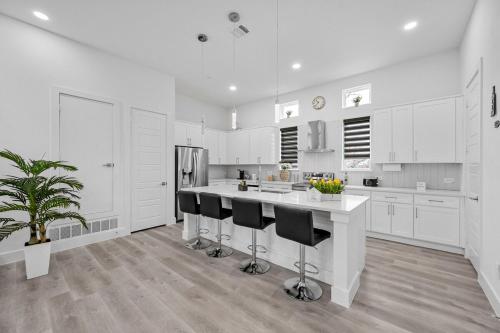 a kitchen with white cabinets and a island with bar stools at BRs w Ensuite Baths l Pet-Friendly l Central Loc in Dallas