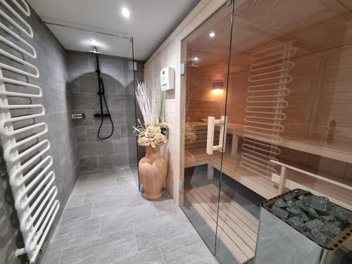 La salle de bains est pourvue d'une douche et d'un vase de fleurs. dans l'établissement Alpine Retreat & Sauna, à Disentis