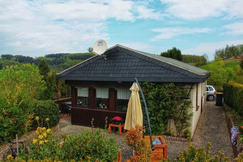 a small shed with a umbrella in a garden at Ferienhaus Bianca in Meschede