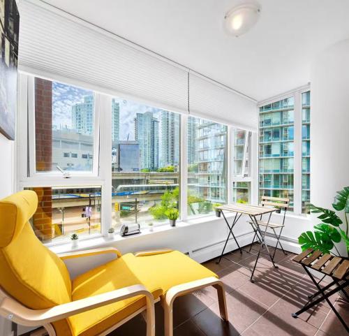 a living room with a yellow couch and a large window at Stylish Condo in Downtown in Vancouver