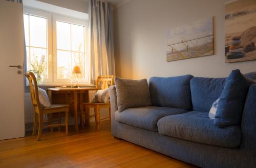 a living room with a blue couch and a table at Windhauch in Westermarkelsdorf