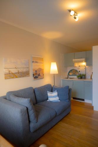 a living room with a blue couch and a kitchen at Windhauch in Westermarkelsdorf