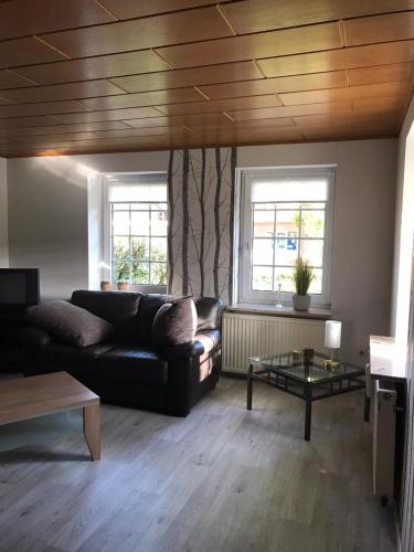 a living room with a black couch and two windows at Ferienhaus auf dem Hof in Wanna