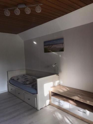 a white bedroom with a bed and a table at Ferienhaus auf dem Hof in Wanna