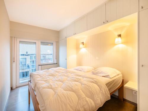 Un dormitorio con una cama grande y una ventana. en Apartment on Belgian Coast with Sea Views, en Oostduinkerke