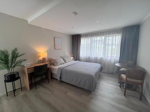 a bedroom with a bed and a desk and a window at Cozy Ensuite Room with Amenities & Private Entrance in Auckland