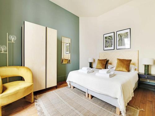une chambre avec un lit blanc et une chaise jaune dans l'établissement Cozy flat 1 BDR 2P - Marais district, à Paris