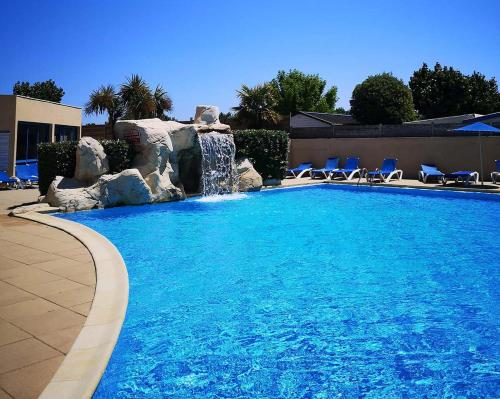 - une piscine avec une cascade et des chaises bleues dans l'établissement Mobil Home avec Clim La Plage, à La Parée Preneau