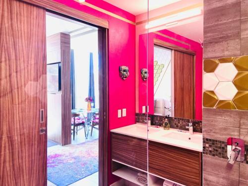 a bathroom with a pink wall with a sink and a mirror at A Breathtaking LUX Home in Puerto Vallarta