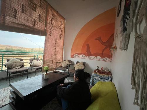 a woman sitting in a living room looking out a window at Pushkar Story in Pushkar