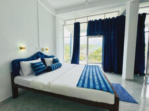 a bedroom with a large bed with blue pillows and a window at Green Peak - Mountain View Hotel & Restaurant in Ella