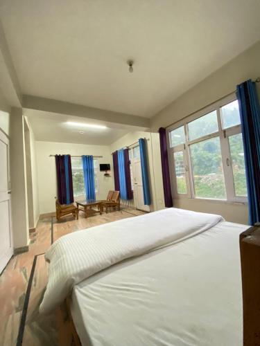 a bedroom with a large white bed with blue curtains at Heaven87 Homestay in Kāndi