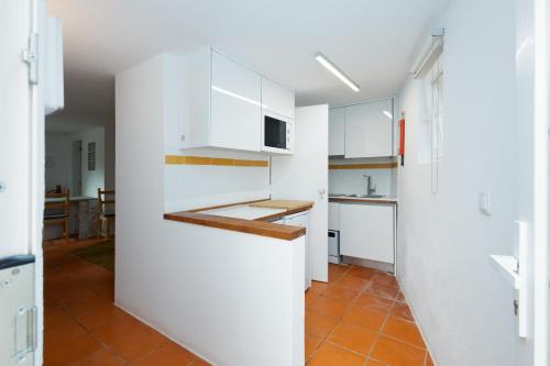 a kitchen with white cabinets and a orange tile floor at Penedo Escape Nature in Colares
