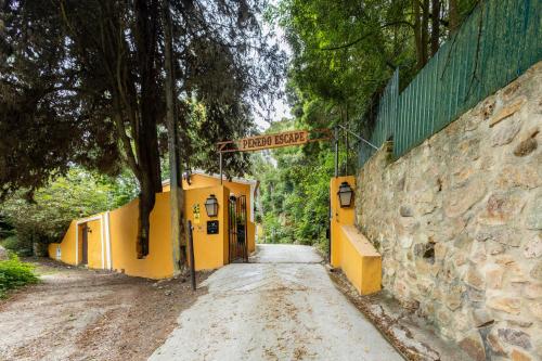 a dirt road with a yellow building next to a stone wall at Penedo Escape Nature in Colares