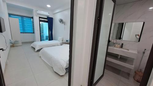 a bedroom with two beds and a sink and a mirror at HT Airport Inn in Phù Xá Ðoài