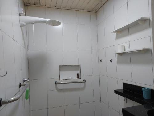 a white tiled bathroom with a shower with a mirror at Flat Aconchego in Porto Velho