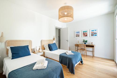 um quarto com 2 camas com lençóis azuis e uma mesa em BeGuest Only Good Vibes - Cabanas em Tavira